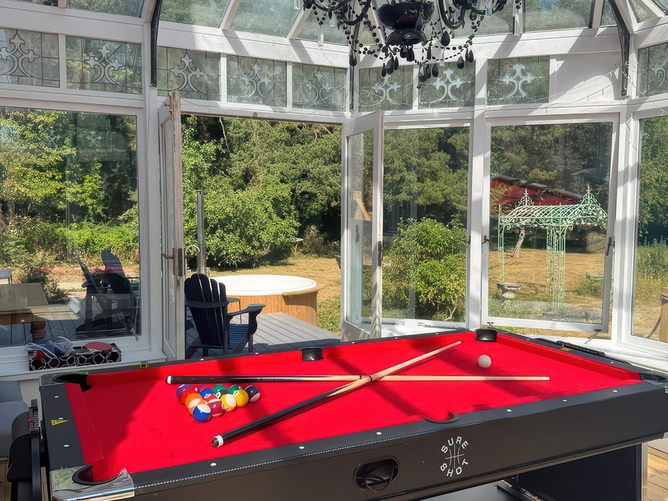 A pool table with balls and cue sticks in a conservatory at Your Country House in Reading