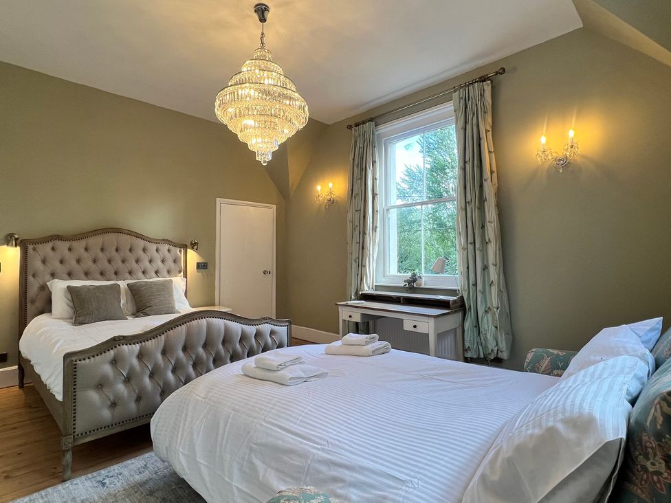 A bedroom with two beds and a chandelier at Your Country House in Reading
