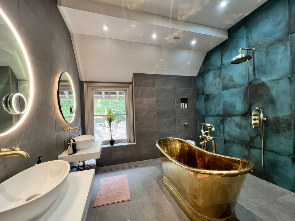 A bathroom with a gold bathtub and dual sinks at Your Country House in Reading