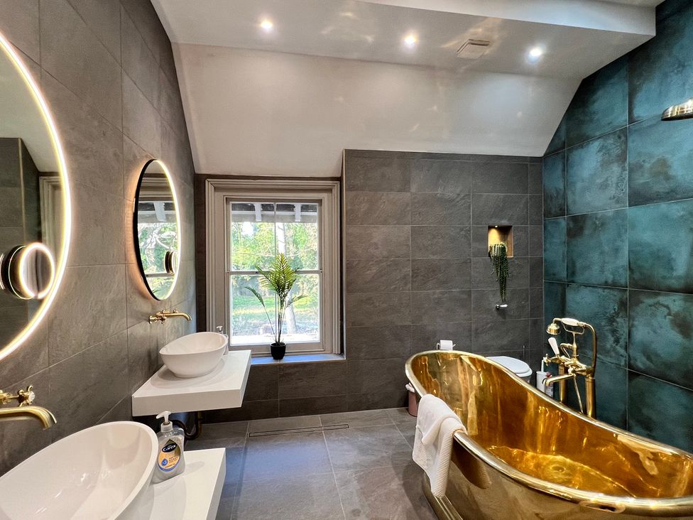A bathroom with a golden bathtub and two sinks at Your Country House in Reading