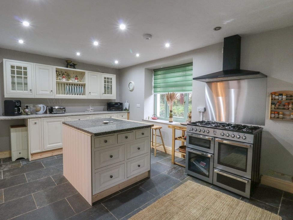 A kitchen with a stove and kitchen island at Penally Mews St Dogmaels