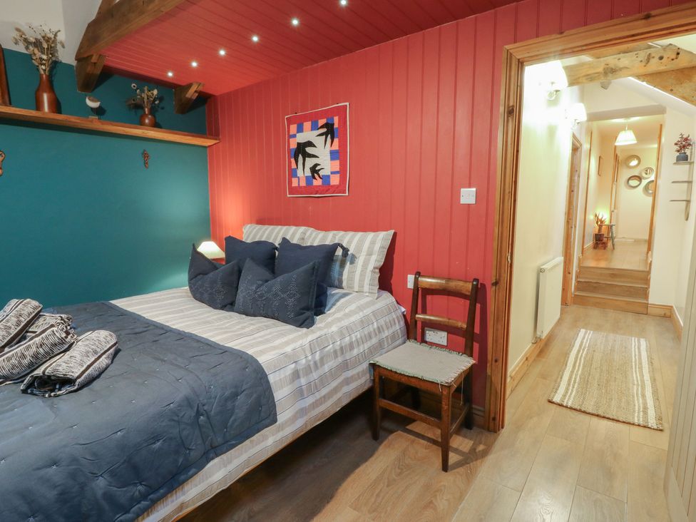 A bedroom with a bed and a chair at Penally Mews in St Dogmaels