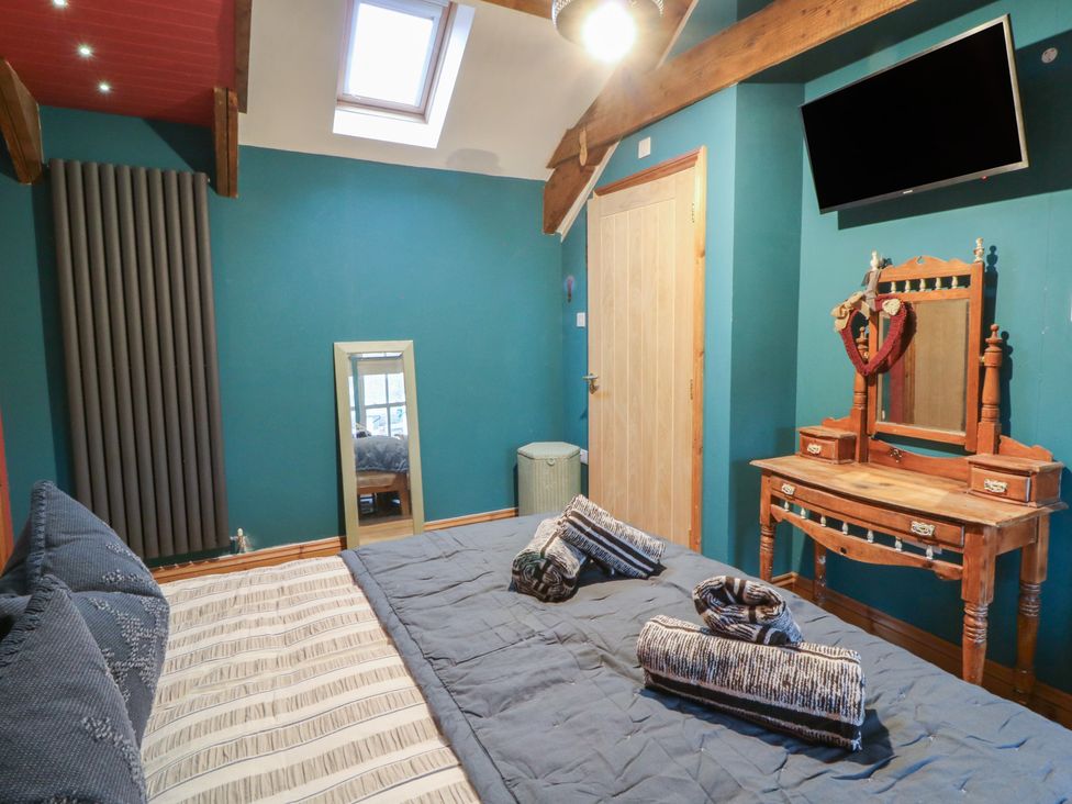 A bedroom with a bed and a dressing table at Penally Mews St Dogmaels
