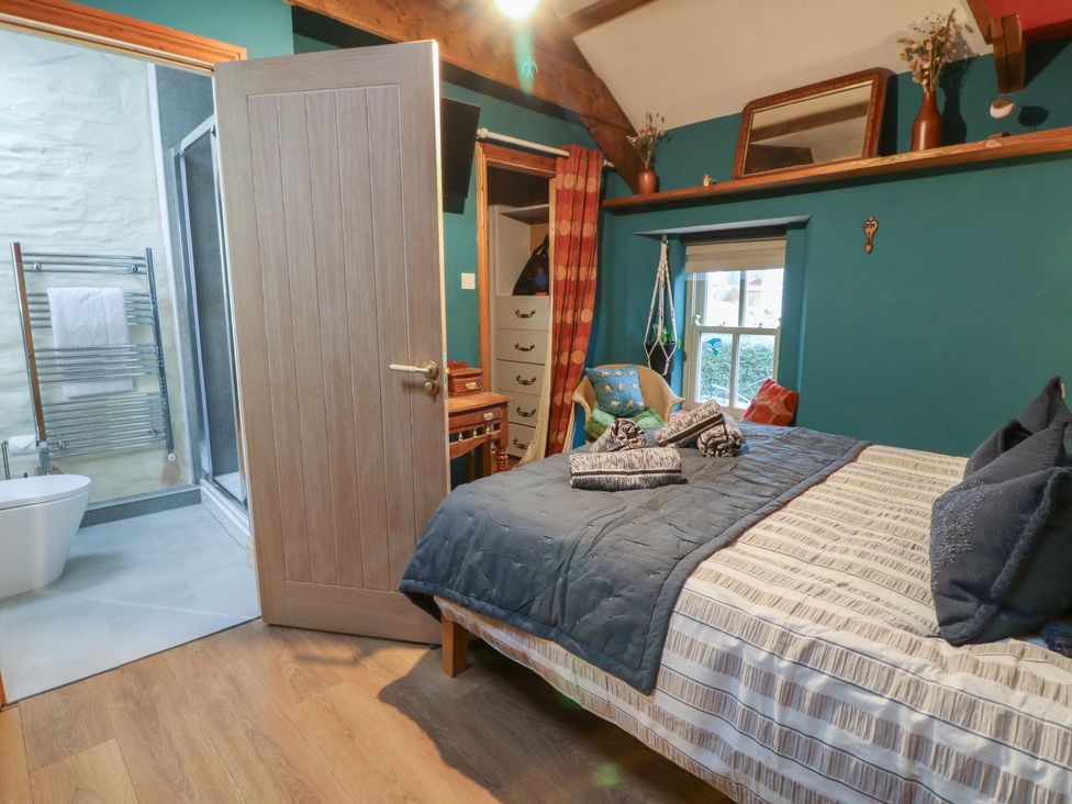 A bedroom with a bed and an ensuite bathroom at Penally Mews in St Dogmaels