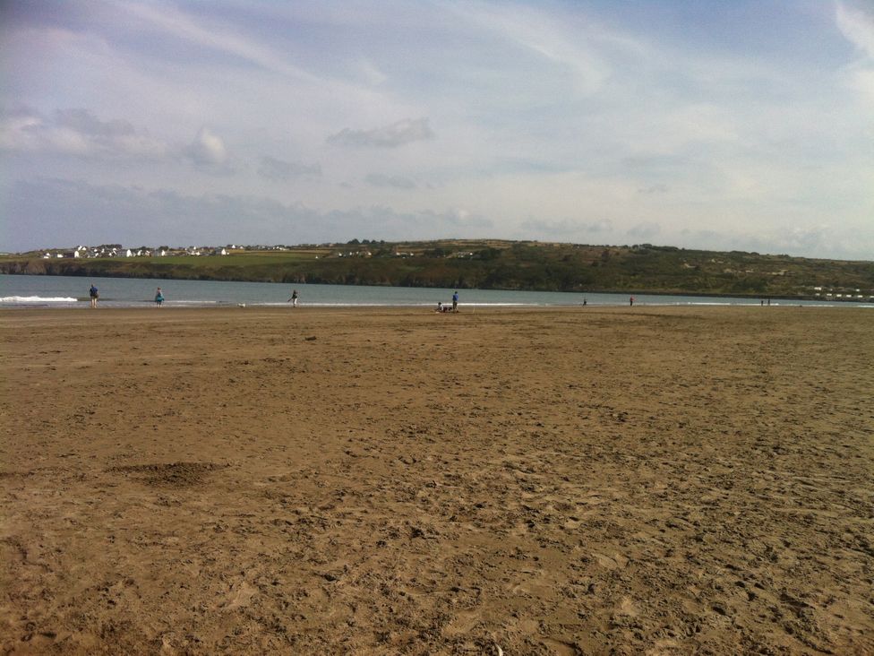 A beach with people walking along the shore at Penally Mews St Dogmaels