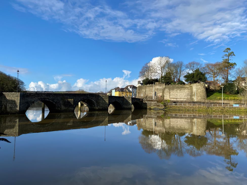 A bridge over a river with trees and buildings at Penally Mews St Dogmaels