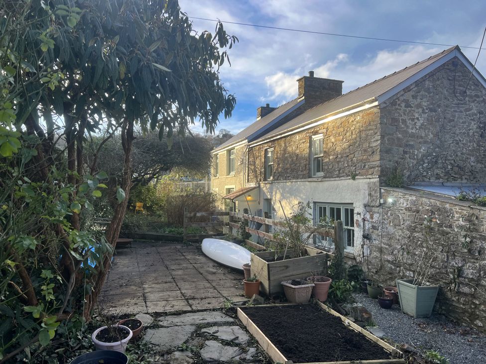 A garden with a house and plants at Penally Mews in St Dogmaels