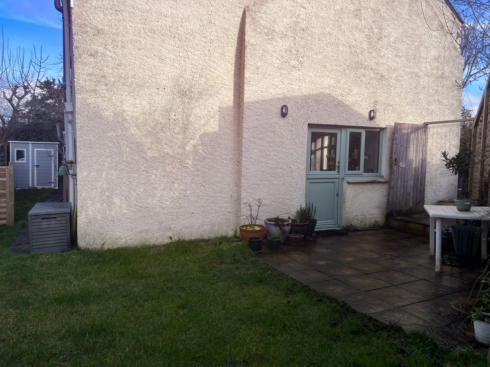 A garden with grass, patio, table and planters at Penally Mews in St Dogmaels