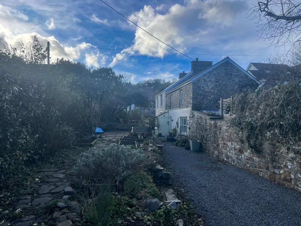 A garden with a pathway and a house at Penally Mews in St Dogmaels