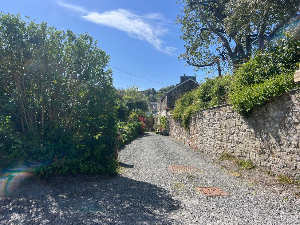 A gravel path with stone walls and greenery at Penally Mews in St Dogmaels