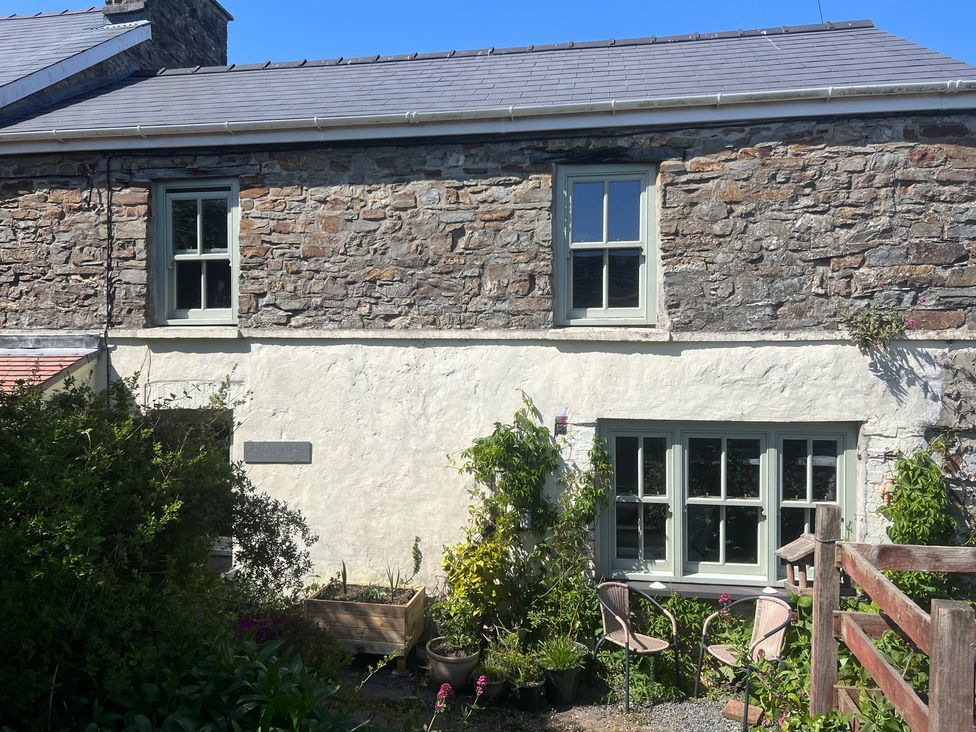 An outdoor area with a stone house and flower boxes at Penally Mews in St Dogmaels