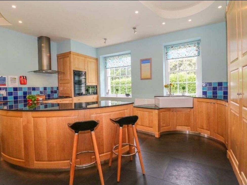A kitchen with wooden cabinets and island at The Old Vicarage in St Issey