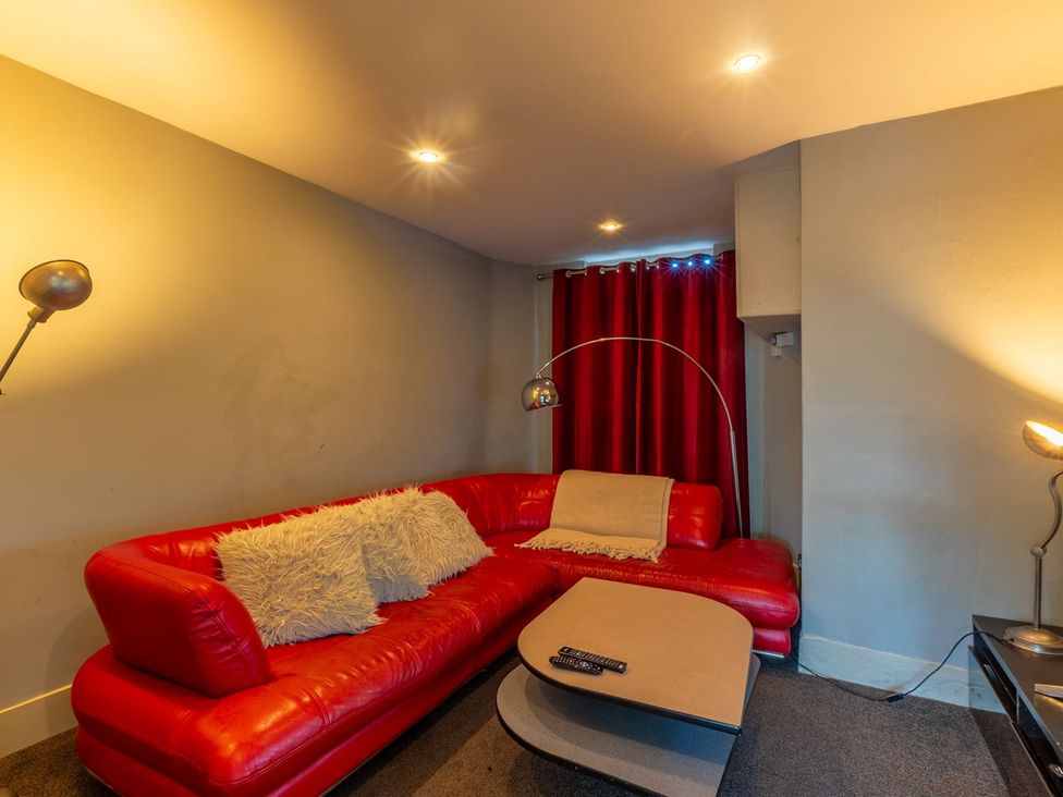 A living room with a red sofa and a coffee table at The Boundary in Windermere