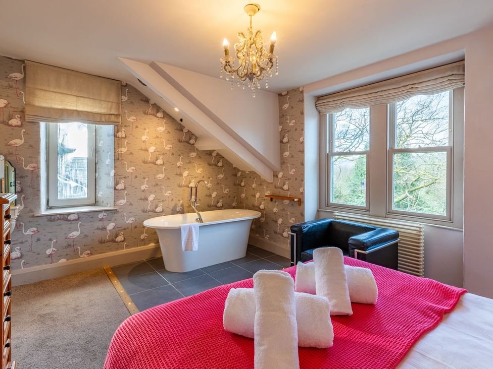 A bedroom with a bathtub and windows at The Boundary in Windermere
