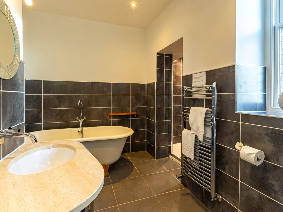 A bathroom featuring a bathtub, sink, towel rack, and shower at The Boundary in Windermere