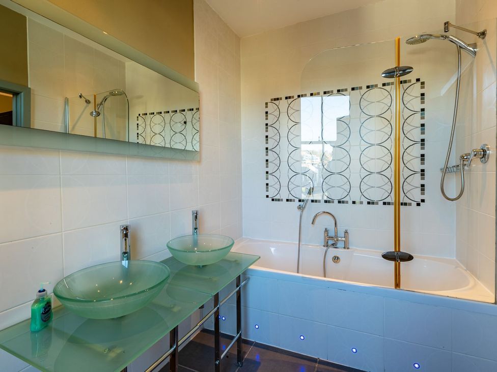 A bathroom with a bathtub, wash basins, and mirror at The Boundary in Windermere
