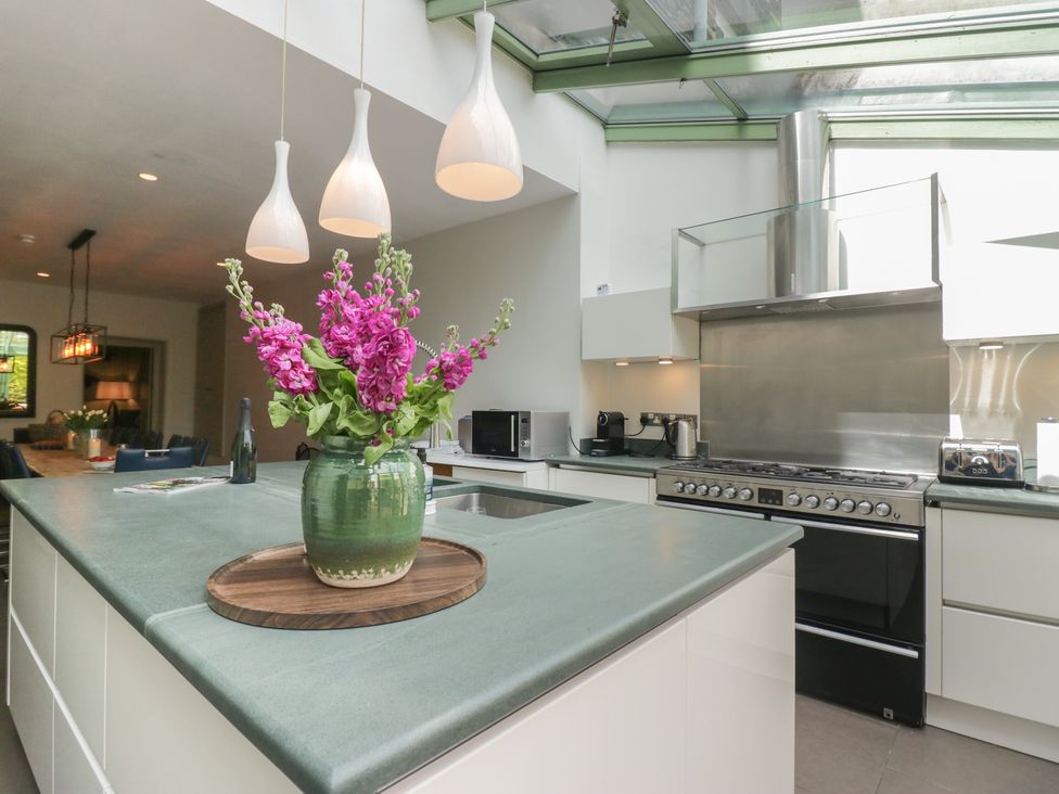 A kitchen with a stove, sink, and flowers in a vase at The Boundary in Windermere