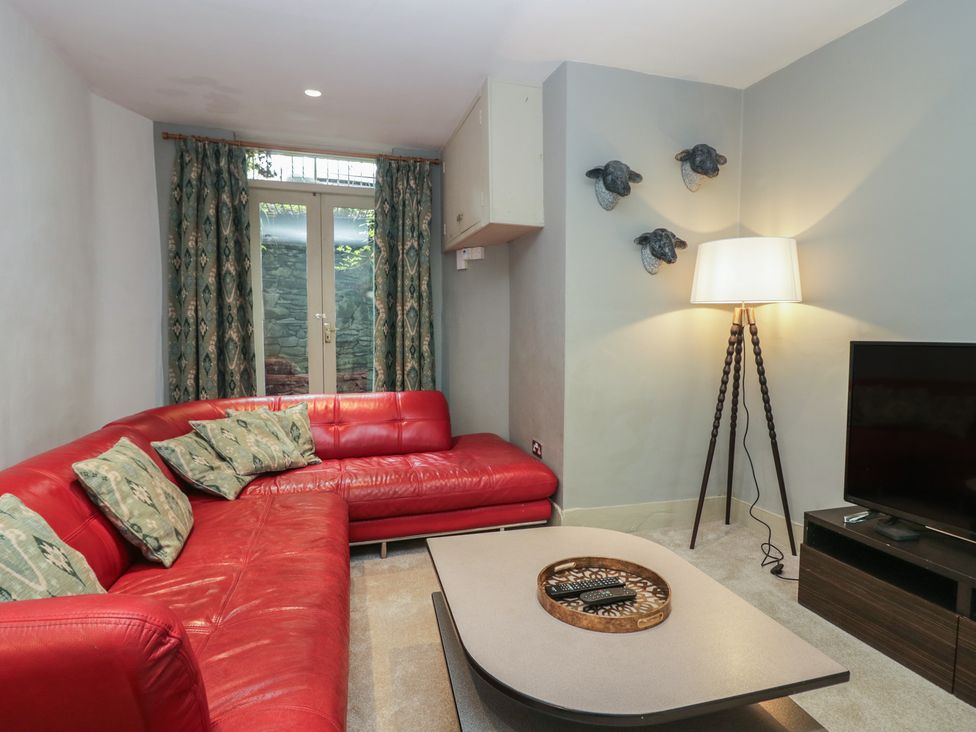 A living room with a red sofa and a television at The Boundary in Windermere