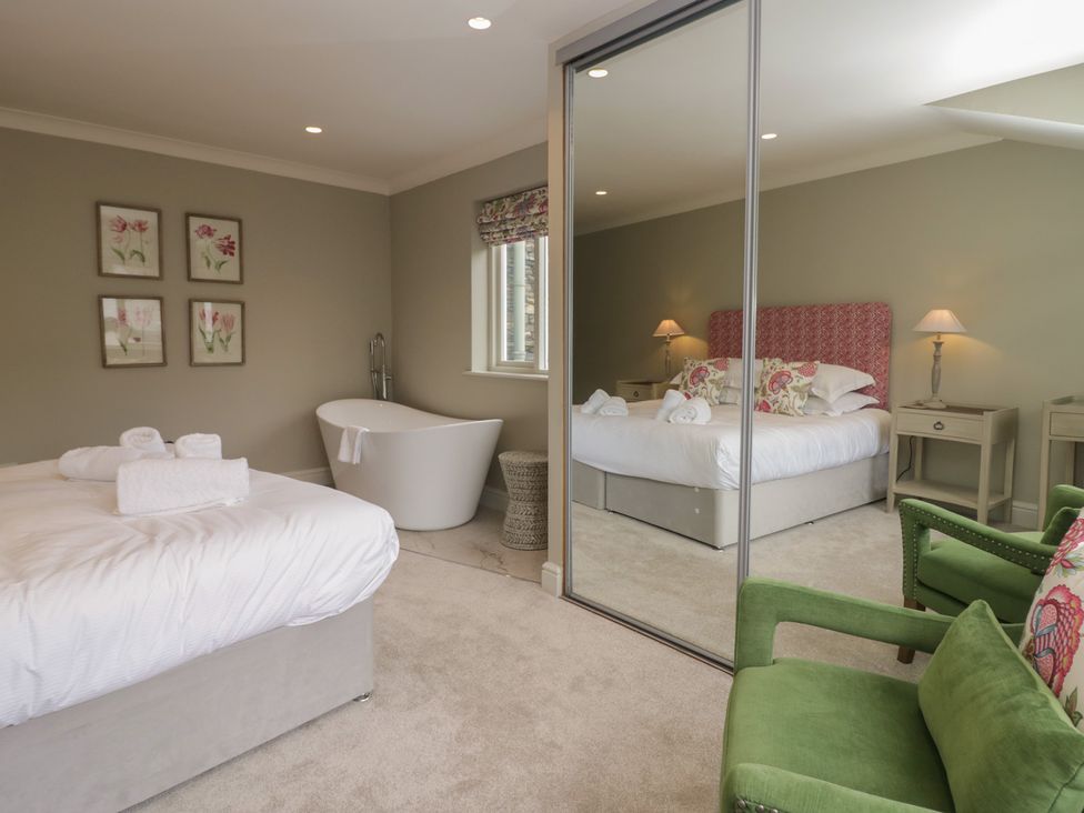 A bedroom with a bed, bathtub, and green chair at The Boundary in Windermere