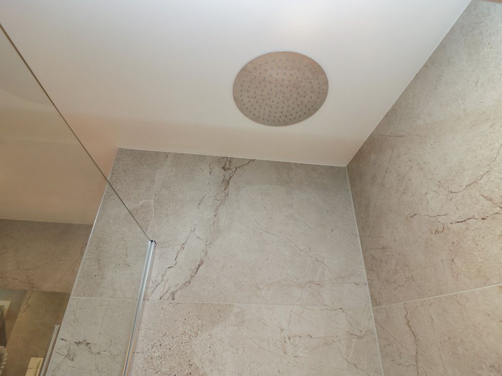 A shower with a rain showerhead and tiled walls at The Boundary in Windermere