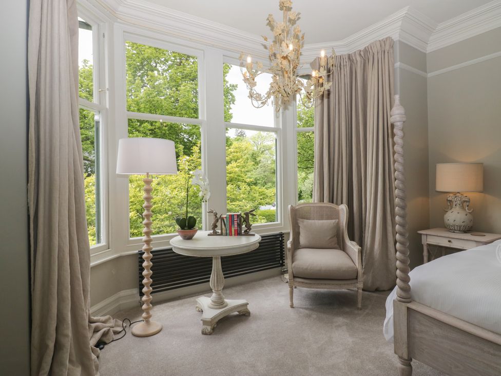 A bedroom with a bed, chair, lamp, and a table at The Boundary in Windermere