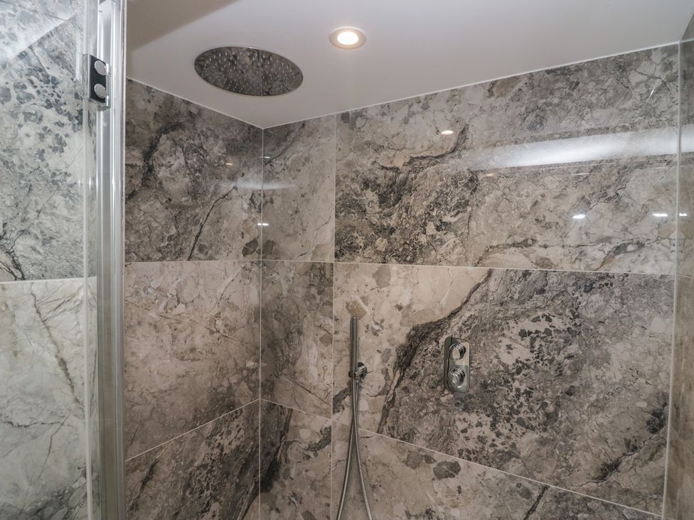 A shower with stone tiles and showerhead at The Boundary in Windermere
