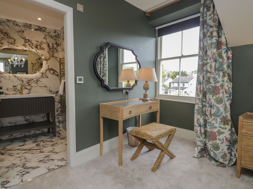 A bedroom with a mirror, lamp, table, and stool at The Boundary in Windermere