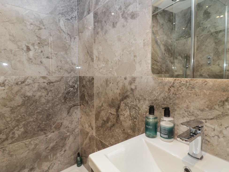 A sink with soap dispensers and tiles in the bathroom at The Boundary in Windermere