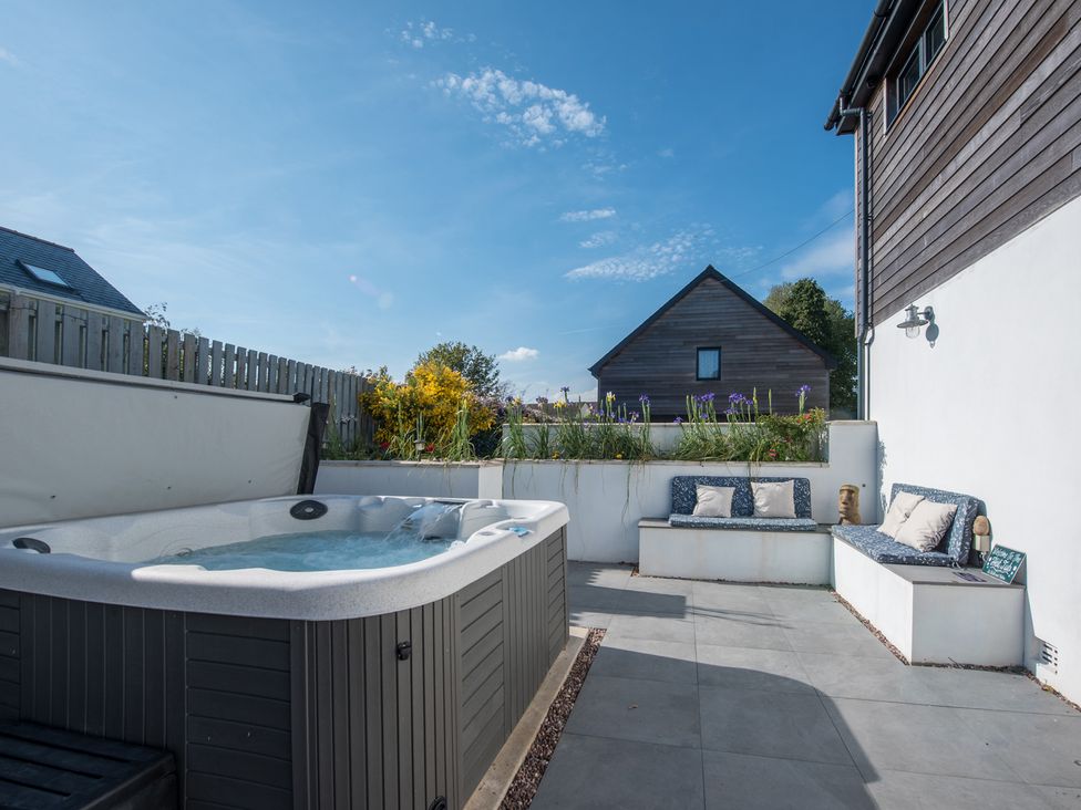 An outdoor area with a hot tub and seating at Sea Haze in Tenby