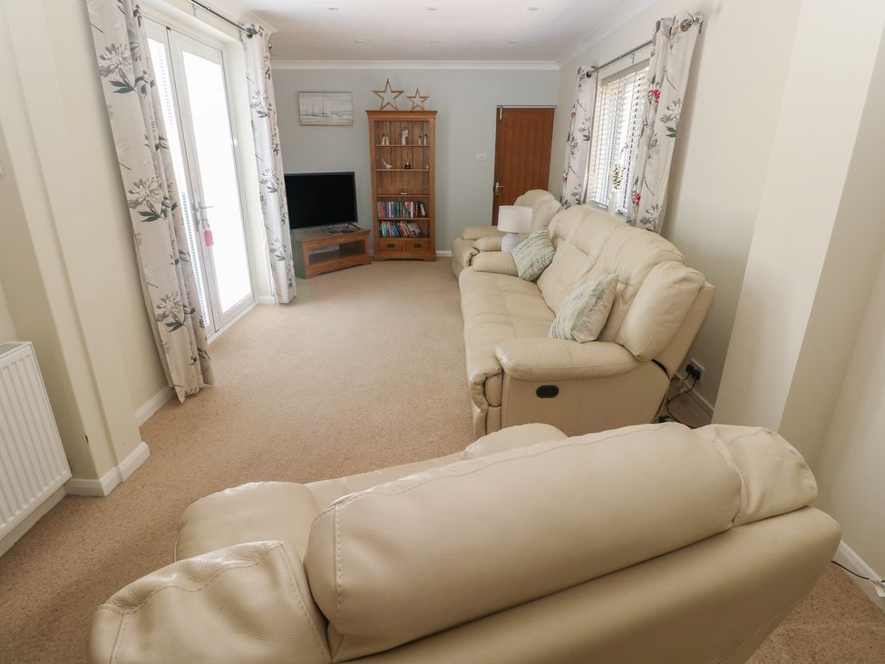 A living room with a sofa and television at Sea Haze in Tenby