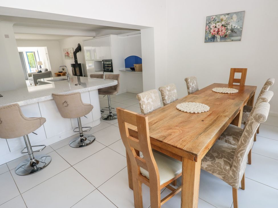 A dining room with a wooden table and bar stools at Sea Haze in Tenby