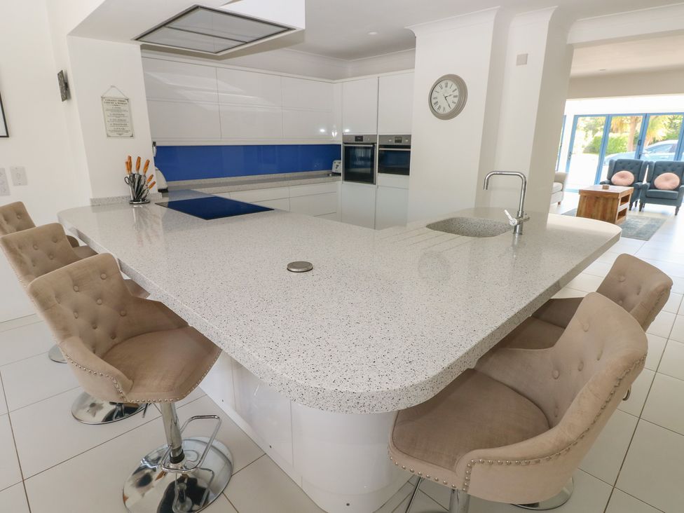 A kitchen with a large island and bar stools at Sea Haze in Tenby