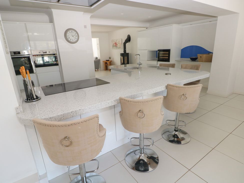 A kitchen with a stone island and bar stools at Sea Haze in Tenby