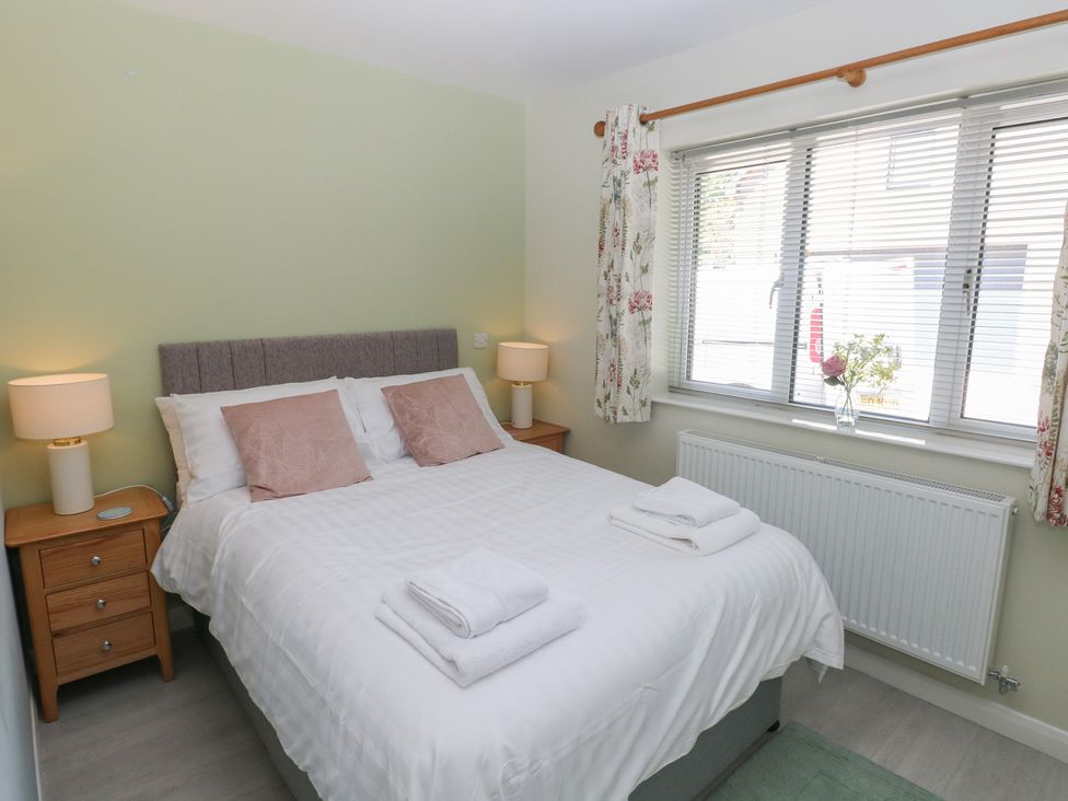 A bedroom with a double bed and curtains at Sea Haze in Tenby