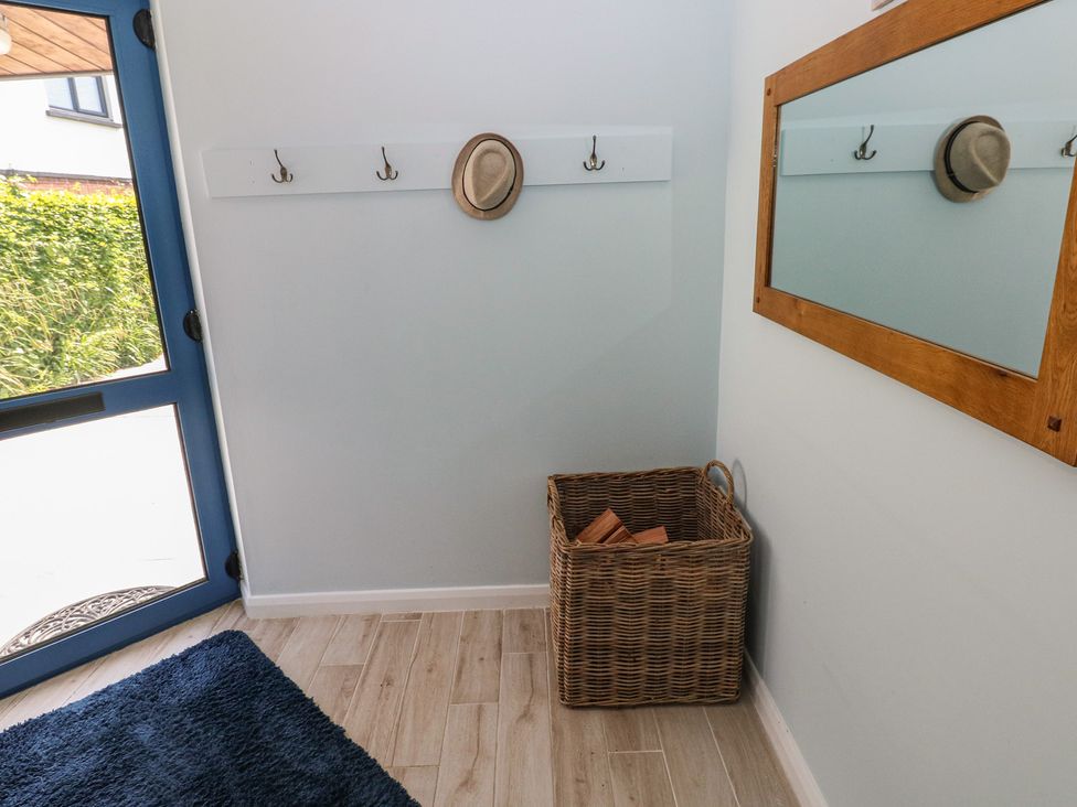 A hallway featuring hooks, a mirror, and a basket at Sea Haze in Tenby