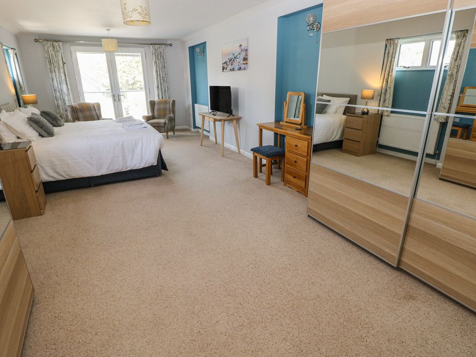 A bedroom with a bed, chairs, and a TV at Sea Haze in Tenby