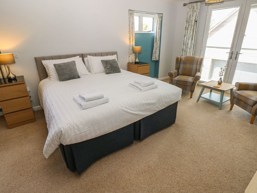 A bedroom with a bed and two chairs at Sea Haze in Tenby