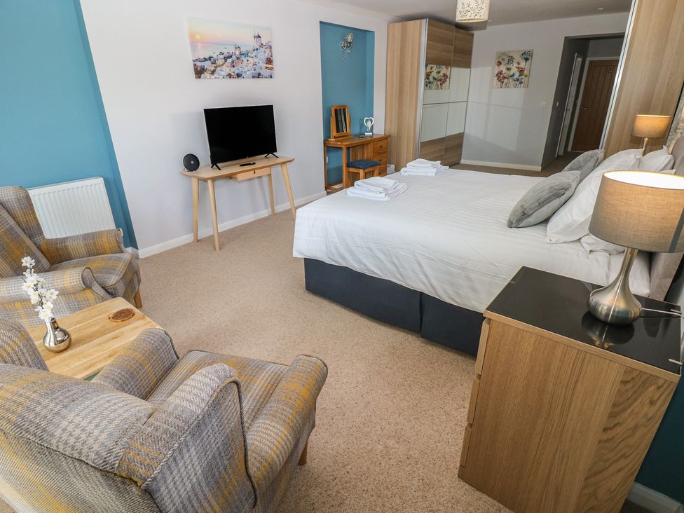 A bedroom with a bed, television, and seating area at Sea Haze in Tenby