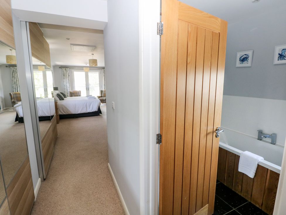 A bathroom with a bathtub and door at Sea Haze in Tenby