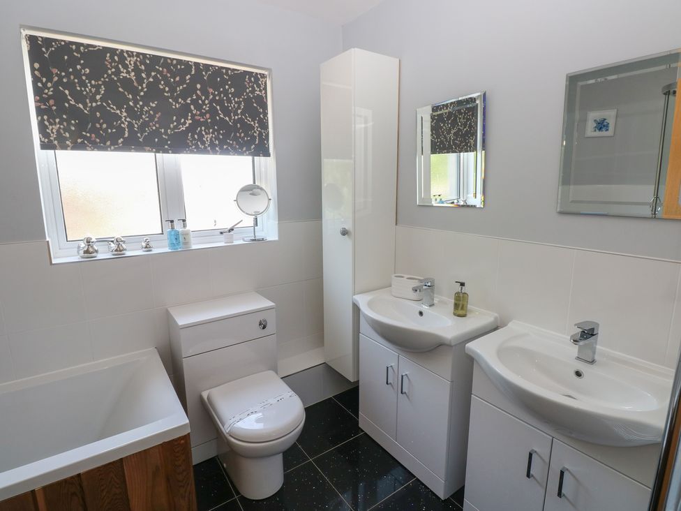 A bathroom with a bathtub, toilet, and sinks at Sea Haze in Tenby