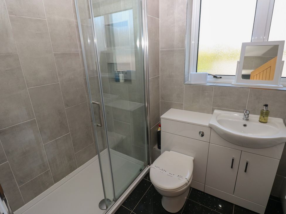 A bathroom with a shower, toilet, and sink at Sea Haze in Tenby