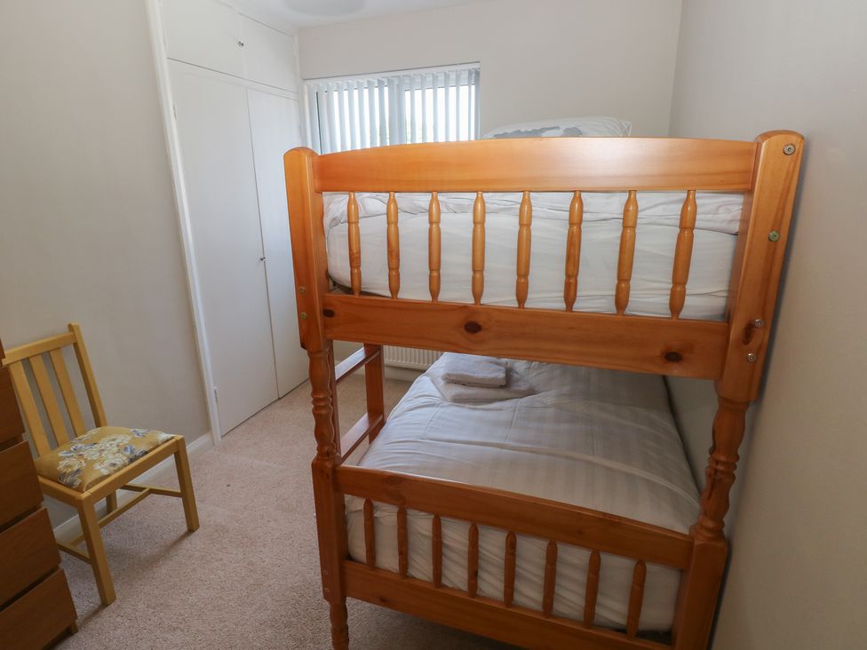 A bedroom with a bunk bed and a chair at Sea Haze in Tenby