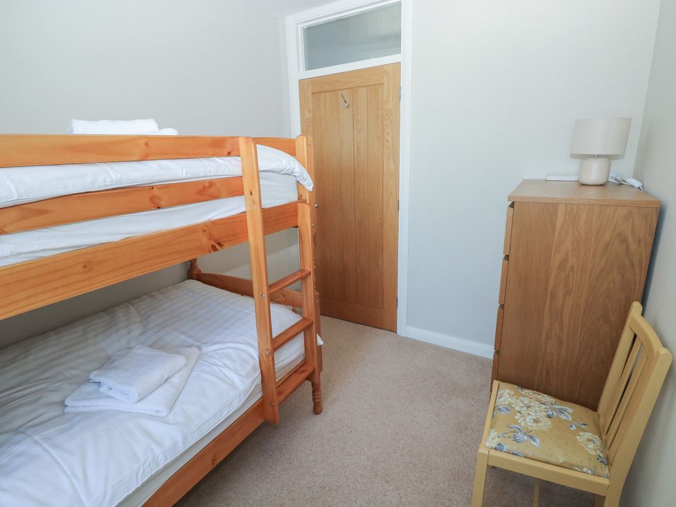 A bedroom with a bunk bed and a chair at Sea Haze in Tenby
