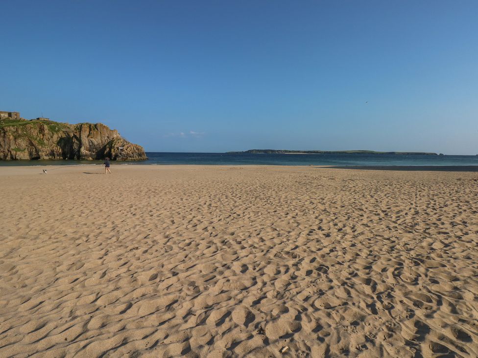 A beach with sand and a person walking at Sea Haze in Tenby