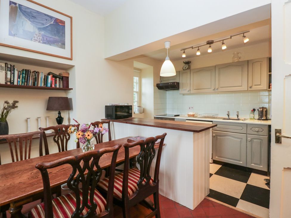 A kitchen with a dining table and bookshelf at The Old Kitchen in Cartmel