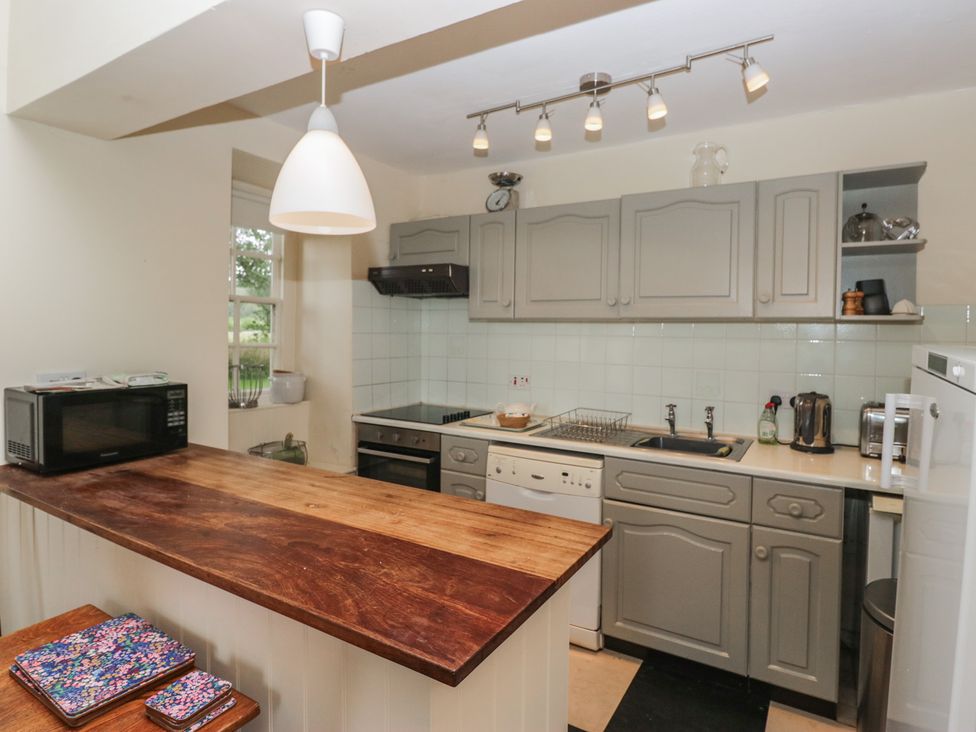 A kitchen with cabinets, stove, microwave, and countertop at The Old Kitchen in Cartmel