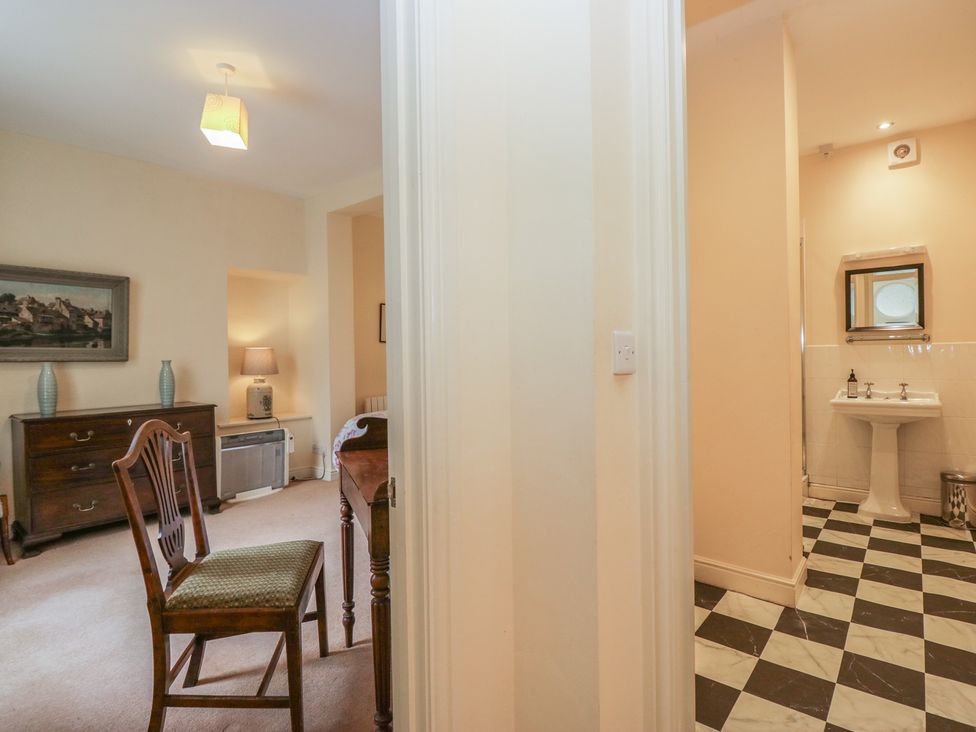 An entrance area with a chair and table leading to a bathroom at The Old Kitchen in Cartmel