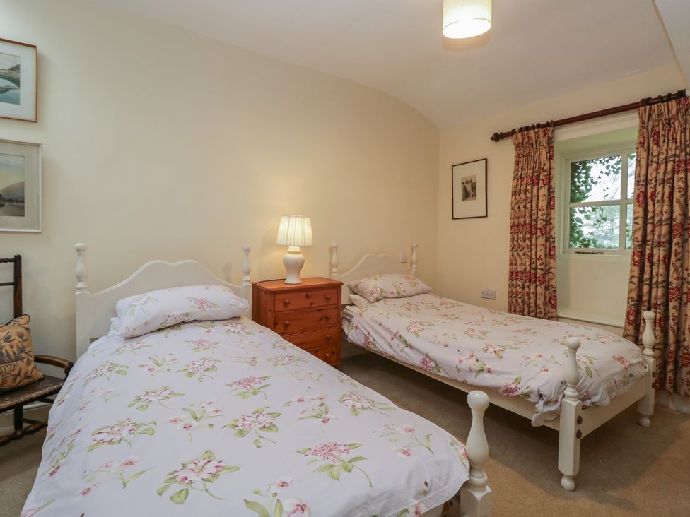 A bedroom with two beds and a lamp on a bedside table at The Old Kitchen Cartmel