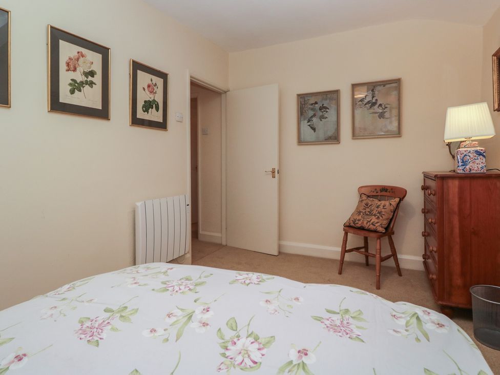 A bedroom with a bed, a cabinet, and wall art at The Old Kitchen in Cartmel