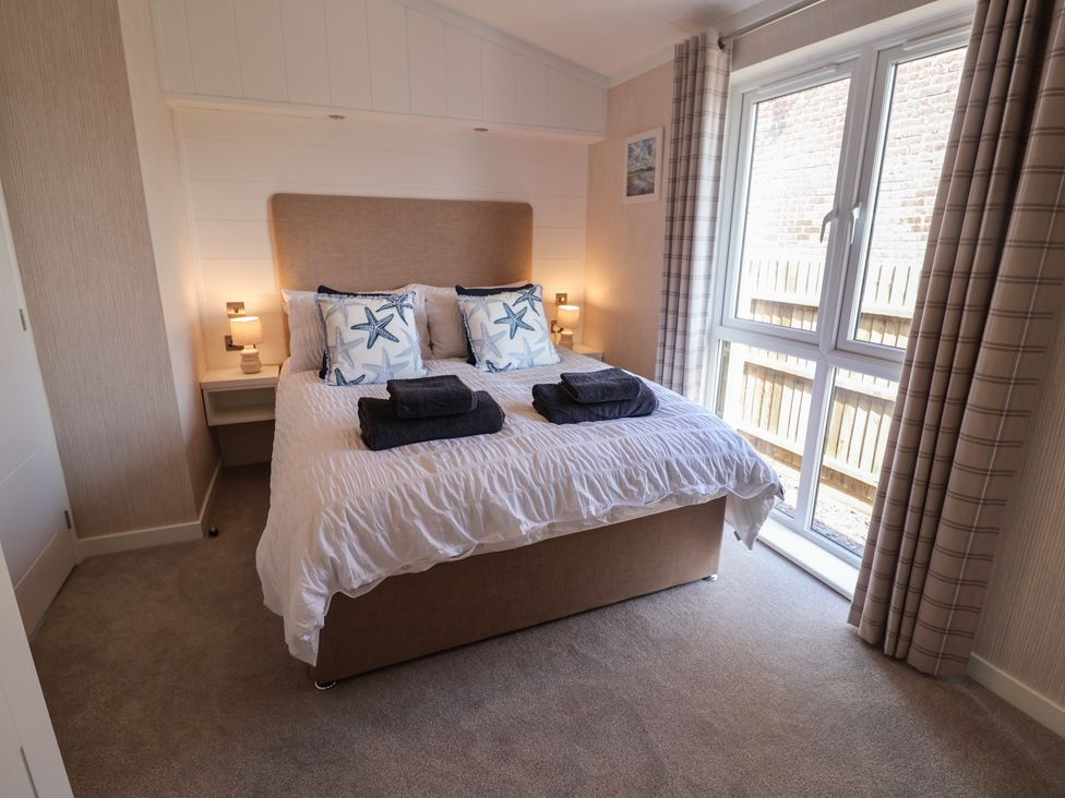 A bedroom with a bed and window at Lodge 1 in Norwich